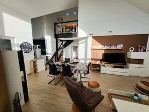 A modern living space with a dining area, kitchen, and a staircase leading to an upper level.