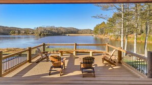 Eine Holzterrasse mit Stühlen mit Blick auf einen See und einen Wald.