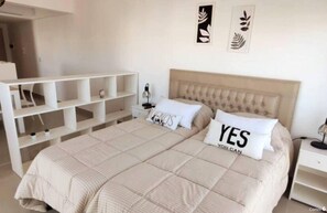 A bedroom with a bed, a nightstand, a shelf unit, and wall art.