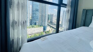 Habitación de hotel con un ventanal que ofrece vistas de edificios altos y una autopista.