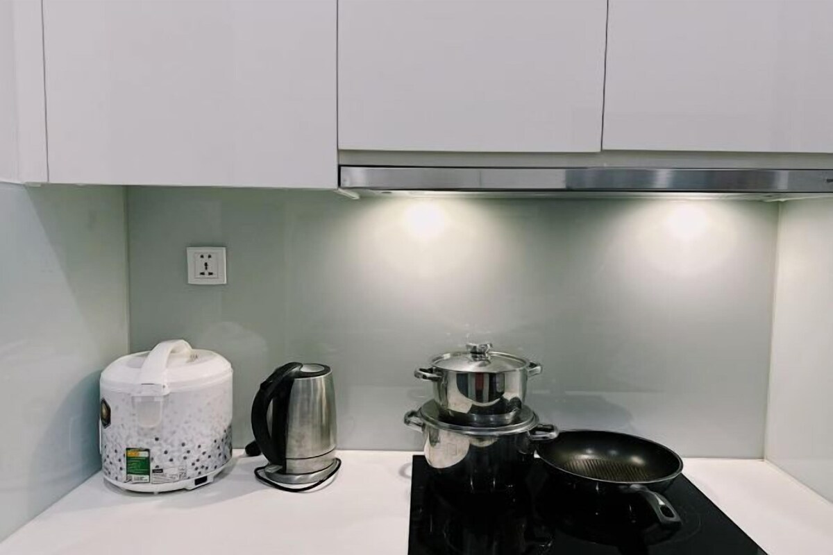 A kitchen with a coffee maker, a kettle, and a frying pan on a stove.