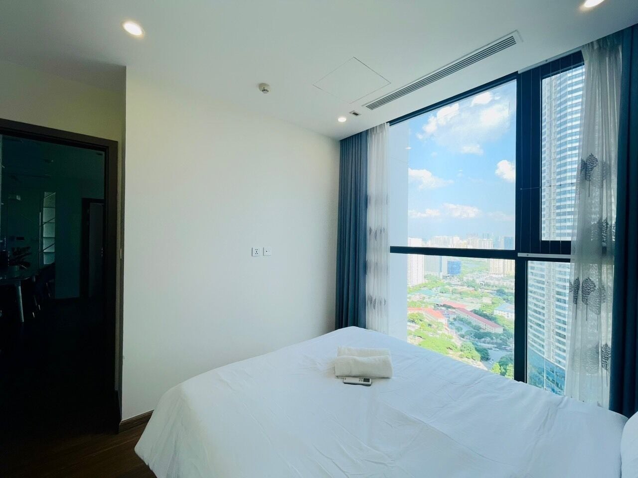 A hotel room with a large bed, a view of the city, and a window with curtains.