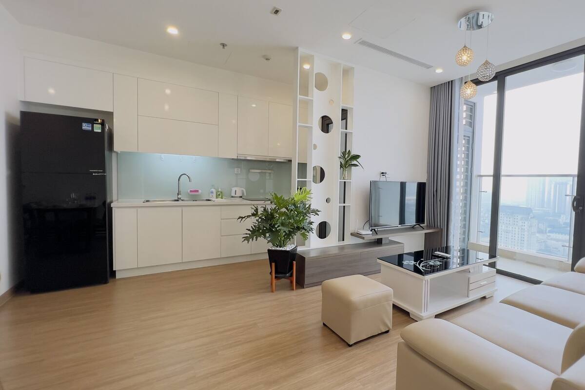 A modern apartment with a kitchen, living area, and large windows offering a city view.