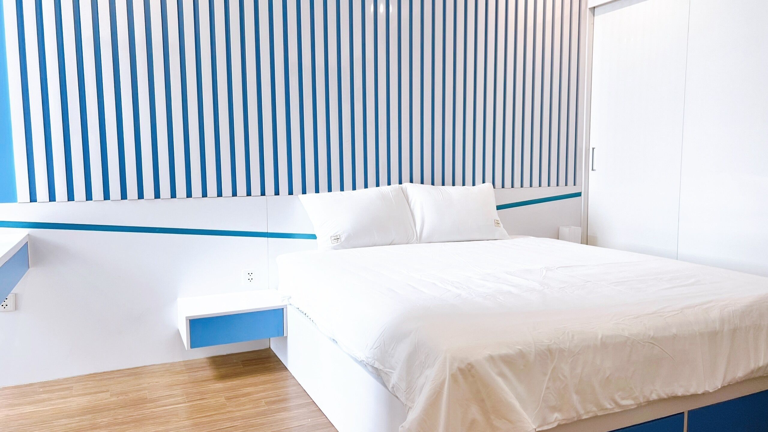 Una habitación de hotel moderna con una cama, una mesita de noche y un panel en la pared.
