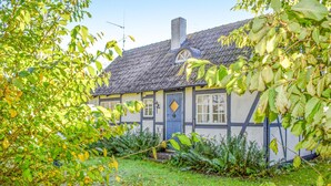 Ein traditionelles Haus mit Strohdach, blauer Tür und Schornstein.
