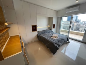 Un dormitorio moderno con cama, armario empotrado y vistas a la ciudad.