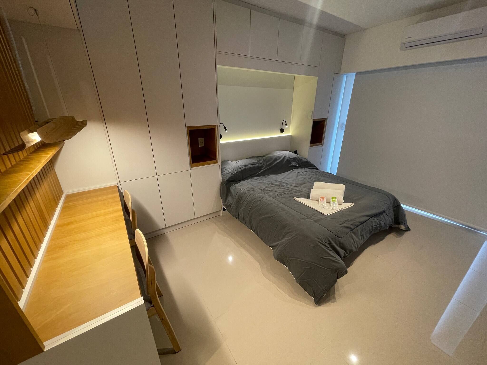 A modern bedroom with a bed, a desk, and a built-in wardrobe.