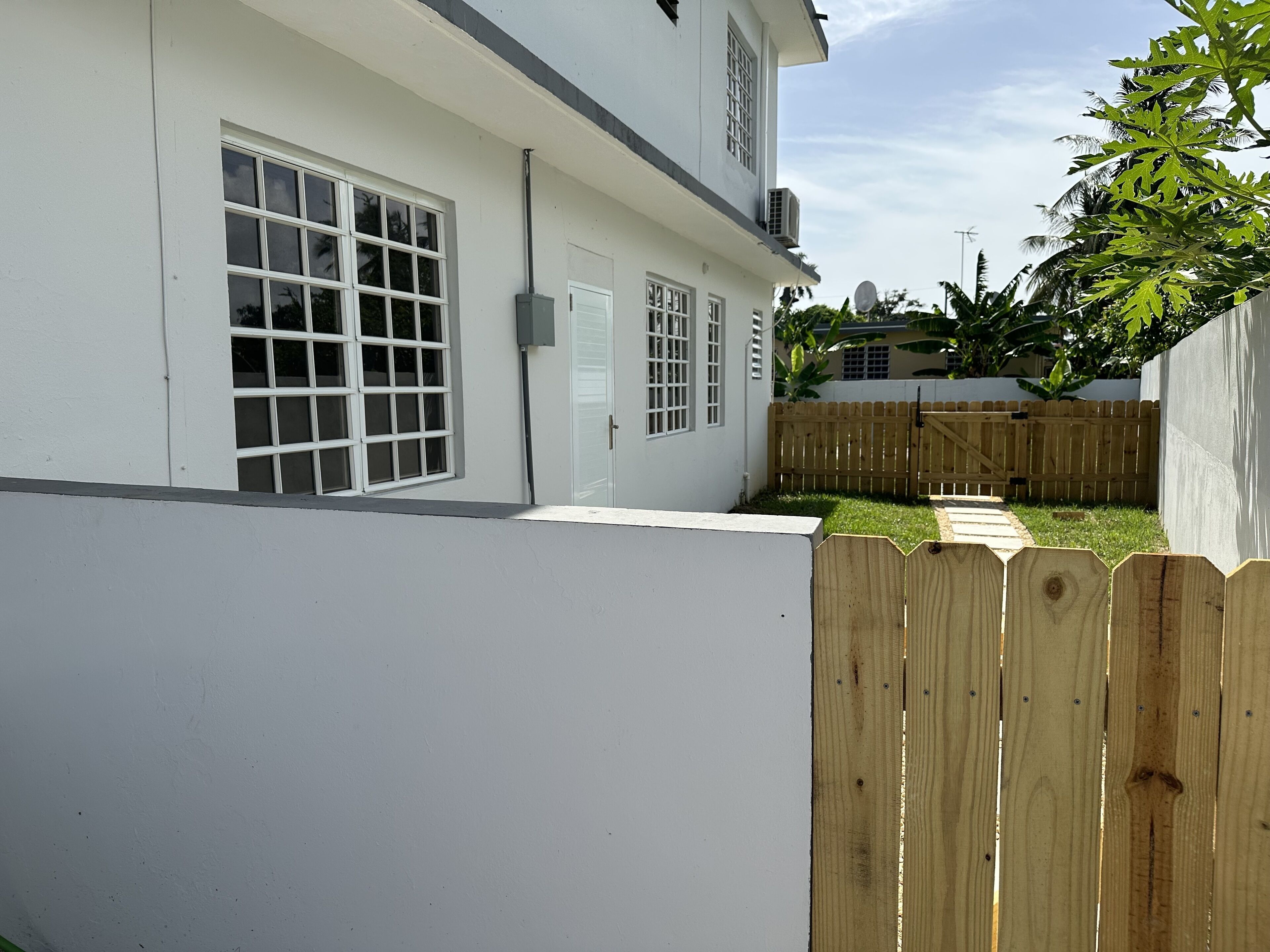 A white building with a wooden fence, a door, and a window.