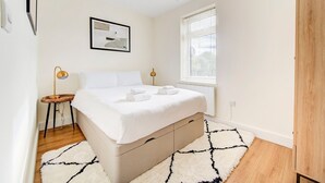 A bedroom with a bed, bedside lamps, a window, and a radiator.