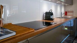Een moderne keuken met een houten aanrecht, een koffieapparaat en een glazen spatwand.