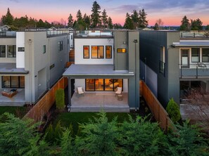 A modern multi-story house with a covered patio and a view of the surrounding forest. - Unobstructed, Breathtaking Water Views RIGHT in Kirkland, WA. (Kirkland)