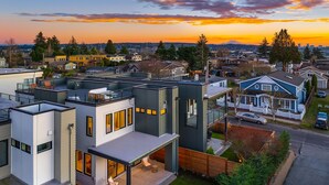 Un quartier résidentiel moderne, avec des maisons contemporaines, une pelouse bien entretenue et une vue dégagée sur le coucher de soleil en arrière-plan.