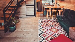 Um interior aconchegante com escada de madeira, área de jantar e sala de estar com sofá verde.