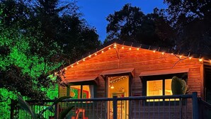 Uma cabana de madeira com varanda, iluminada por luzes de Natal.