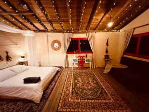 Une chambre confortable avec un lit, un bureau et une chaise. On y trouve une fenêtre avec des rideaux, une horloge murale et un luminaire suspendu.