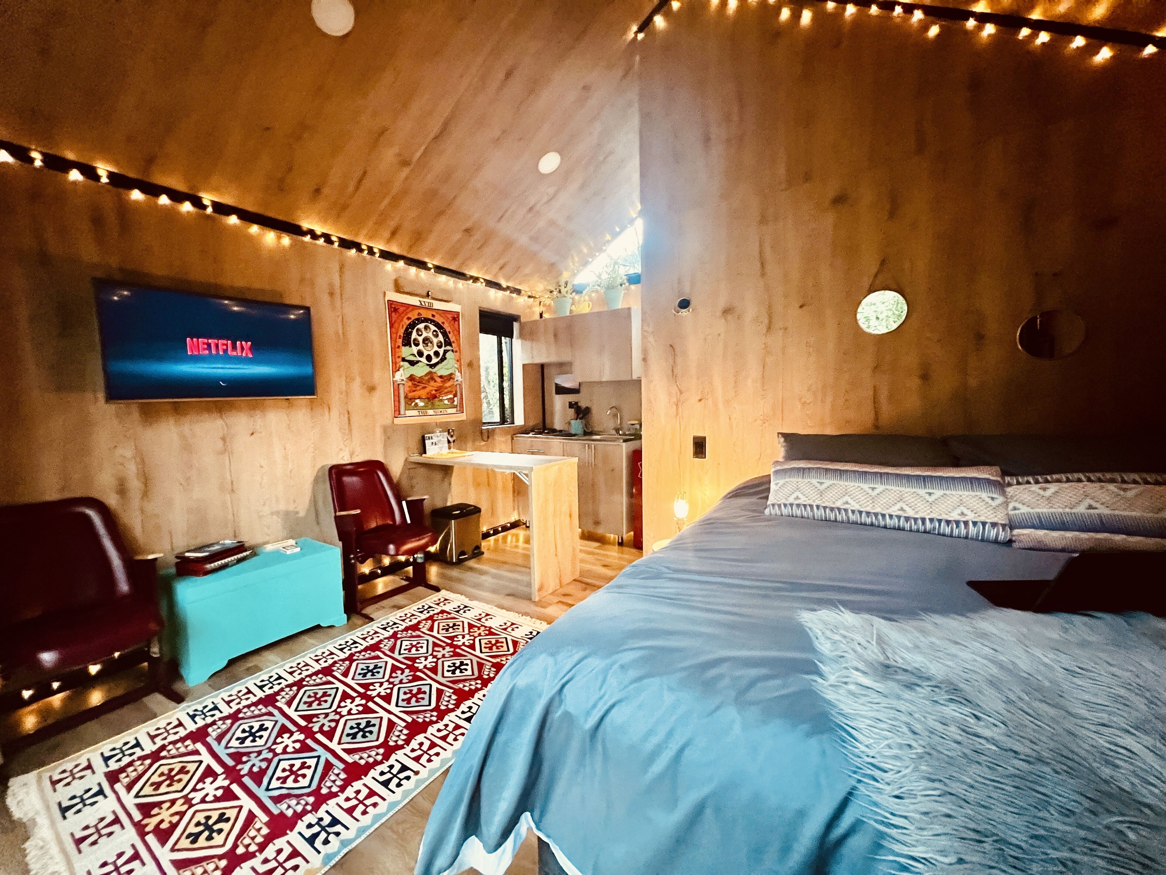 A cozy room with a bed, a desk, and a TV displaying 'NETFLIX'.