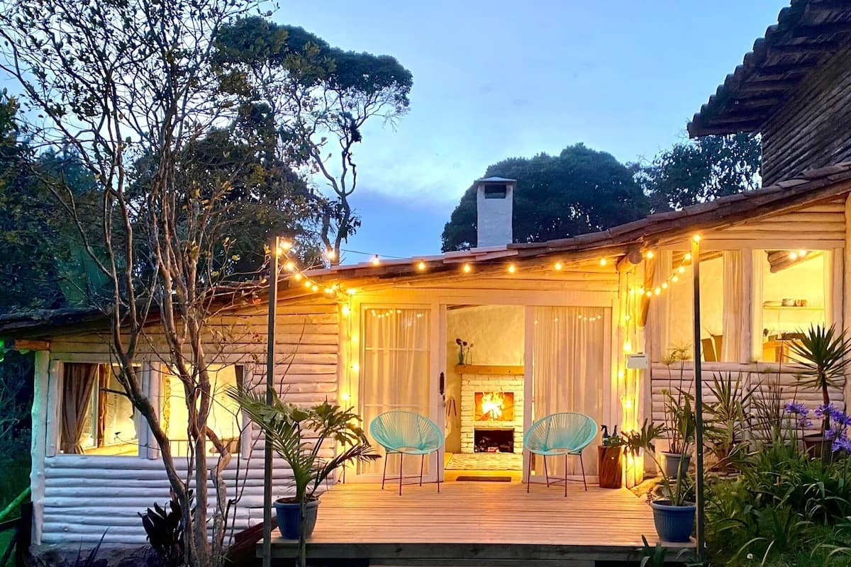 Een gezellig vakantiehuisje met een houten terras, een open haard en sfeerverlichting.