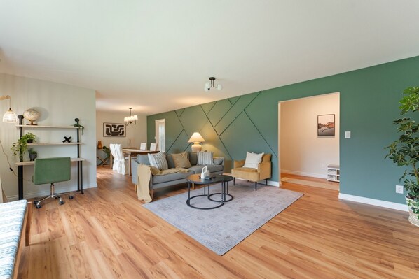 A modern living room with a sofa, coffee table, and a dining area with a table and chairs.