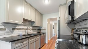 Una cocina moderna con armarios de colores claros, encimera negra y campana extractora de acero inoxidable.