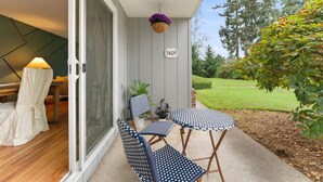Un espacio de estar al aire libre cubierto con una mesa, sillas, una planta colgante y un letrero con el número de la casa.