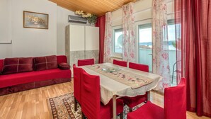 A room with a wooden ceiling, a red sofa, a dining table with floral tablecloth, and red chairs. - Stunning apartment in Crikvenica with WiFi (Crikvenica)