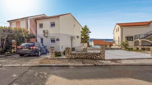 A residential building with a stone gate, a parked car, and a clear view of the sea. - Stunning apartment in Crikvenica with WiFi (Crikvenica)