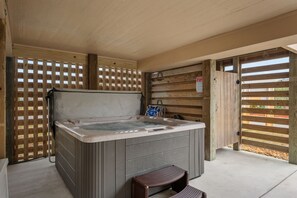 A hot tub area with a wooden deck, a bench, and a wooden fence.