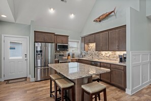 Una cocina moderna con una isla grande, electrodomésticos de acero inoxidable y armarios de madera.
