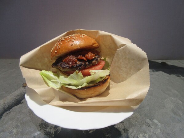 A burger in a paper container on a table.