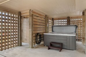 A room with a wooden partition, a hot tub, and a small wooden stool. - Bodie Island Cottage: Semi-Oceanfront, Hot tub and Community Pool (Nags Head)