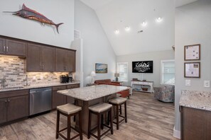 A modern kitchen with a large island, wooden cabinets, and a backsplash. - Bodie Island Cottage: Semi-Oceanfront, Hot tub and Community Pool (Nags Head)