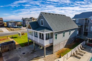 A two-story house with a balcony, a driveway, and a view of the ocean.