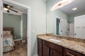 A bathroom with a granite countertop, a sink, and a mirror.