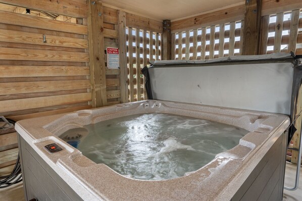 A hot tub with a control panel, surrounded by wooden walls and a window with a view.