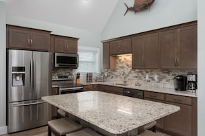 A modern kitchen with stainless steel appliances, granite countertops, and wooden cabinets.