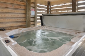 A hot tub with a wooden interior and a caution sign.