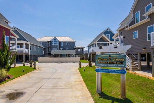 A residential complex with a central building and multiple houses. A sign indicates it is a private beachside resort.