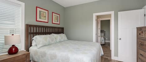 Un dormitorio con cama, mesita de noche, cómoda y ventilador de techo.