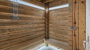 Une cabane en bois avec un espace douche, une porte et une fenêtre.