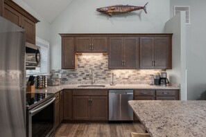 A modern kitchen with dark wood cabinets, a stainless steel dishwasher, and a granite countertop.