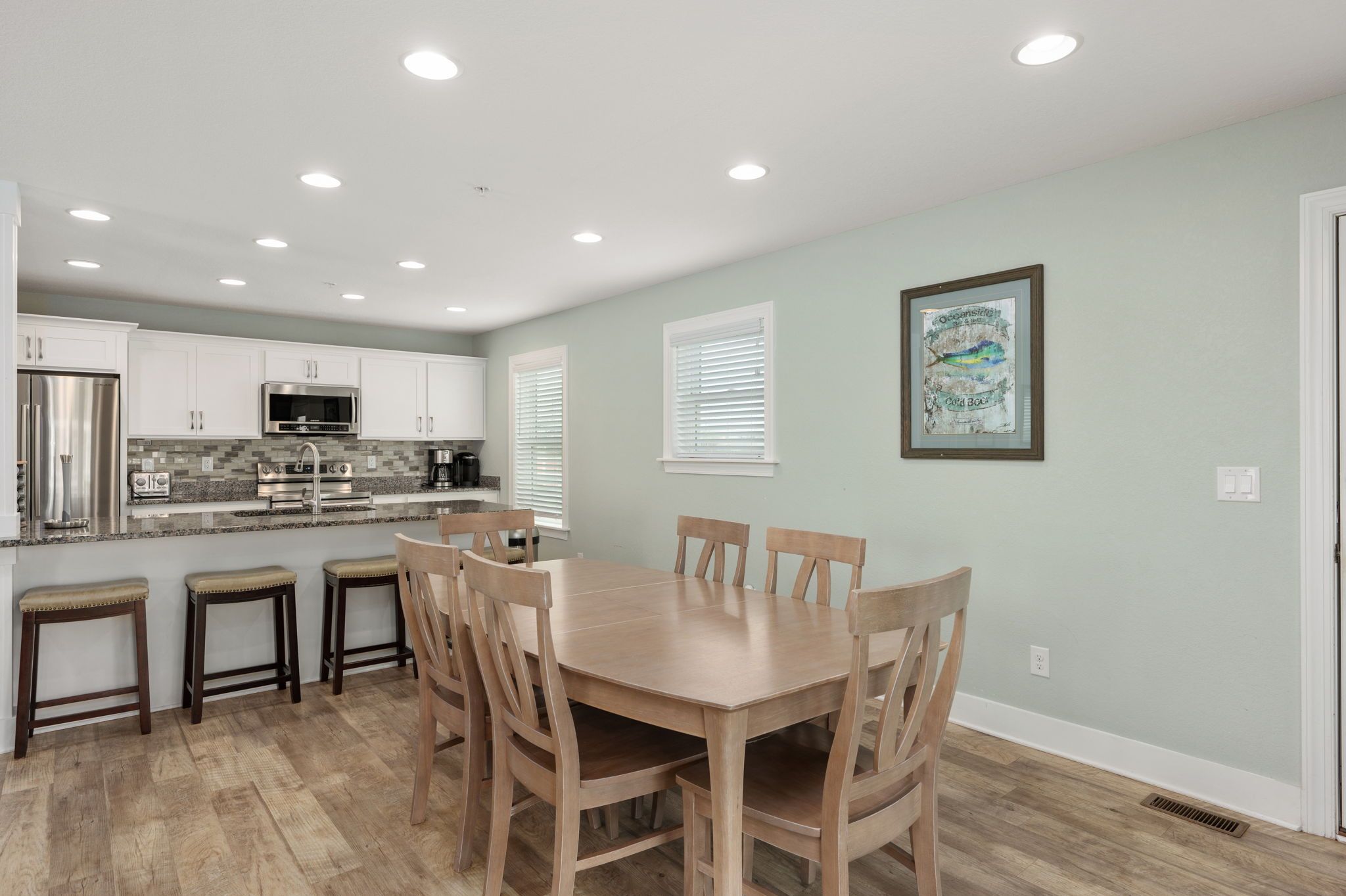 A modern kitchen with white cabinets, a stainless steel refrigerator, and a granite countertop.