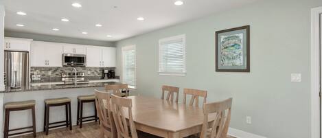 A modern kitchen with white cabinets, a stainless steel refrigerator, and a granite countertop.