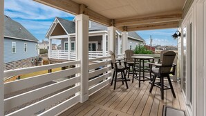 Eine überdachte Veranda mit Holzterrasse, weißen Geländern und Gartenmöbeln.