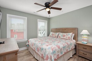 A bedroom with a bed, a nightstand, a desk, and a ceiling fan. - Currituck Cottage: Semi-Oceanfront, Private Hot Tub, Community Pool Access! (Nags Head)