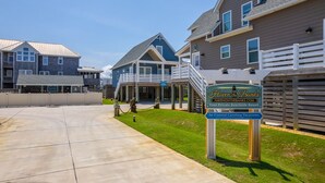 Resort na praia com vários edifícios, uma galeria coberta e uma placa indicando 'Cavern on Banks' pela Coastal Carolina Vacations.