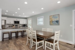Une cuisine moderne avec des meubles blancs, une table à manger avec des chaises et des spots encastrés au plafond.