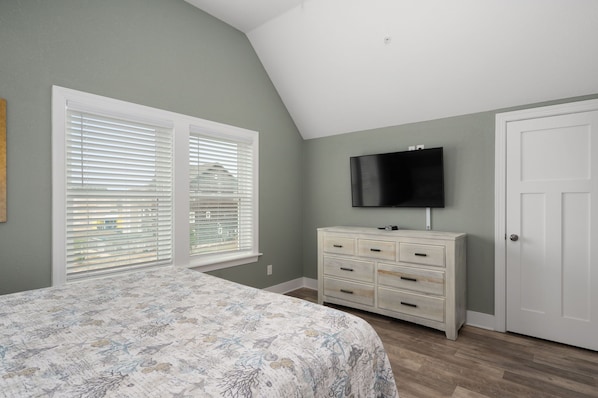 A bedroom with a bed, a dresser, a television, and a door. - Currituck Cottage: Semi-Oceanfront, Private Hot Tub, Community Pool Access! (Nags Head)