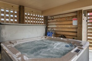 Un bain à remous avec une terrasse en bois et un panneau indiquant les règles d’utilisation du spa.