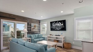 Uma sala de estar moderna com uma televisão grande, sofá azul claro e uma parede de destaque em madeira.