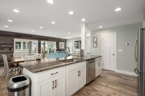 A modern kitchen with a granite countertop, stainless steel appliances, and a central island. - Currituck Cottage: Semi-Oceanfront, Private Hot Tub, Community Pool Access! (Nags Head)